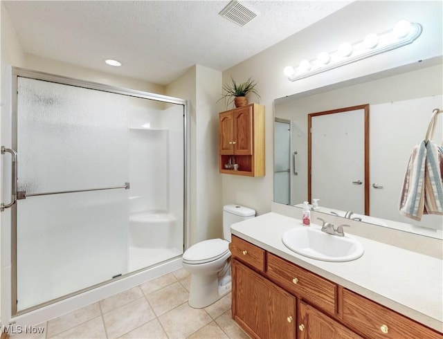 bathroom featuring tile patterned flooring, vanity, toilet, a shower with door, and a textured ceiling