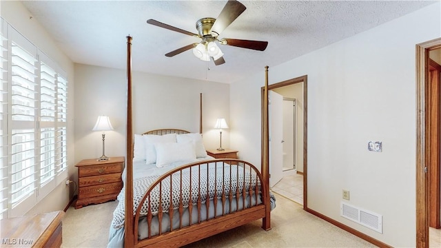 bedroom featuring light colored carpet, a textured ceiling, and ceiling fan