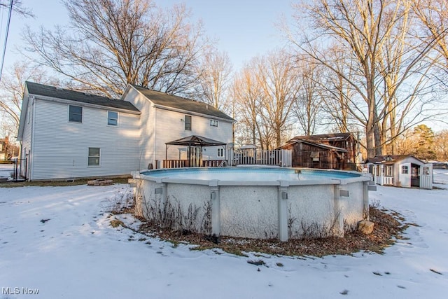 snow covered rear of property featuring a gazebo and a storage unit