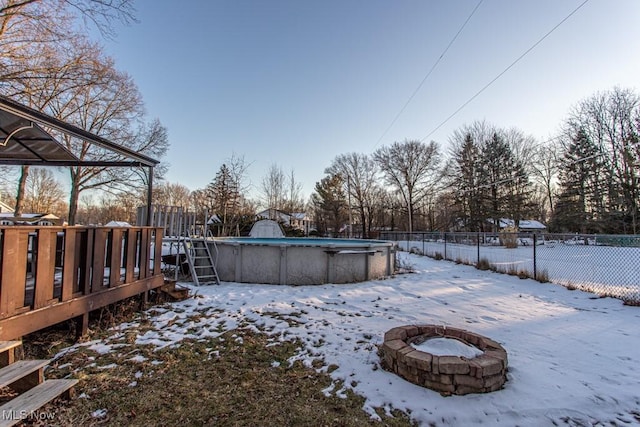 yard layered in snow with a pool side deck and an outdoor fire pit