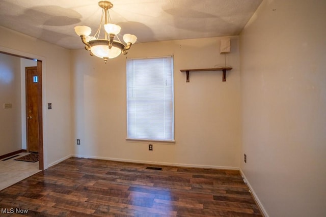 unfurnished room with dark hardwood / wood-style flooring and a chandelier