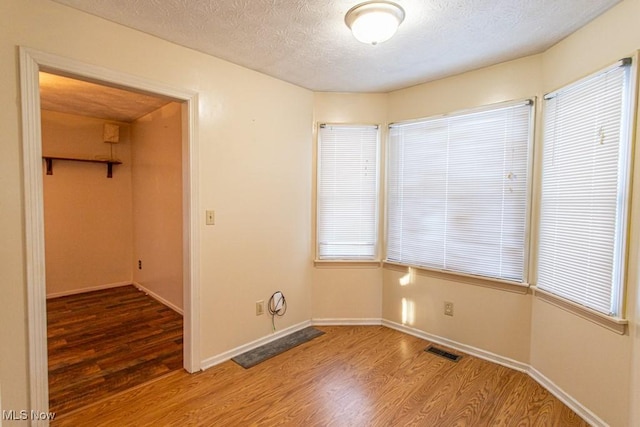 empty room with hardwood / wood-style floors and a textured ceiling