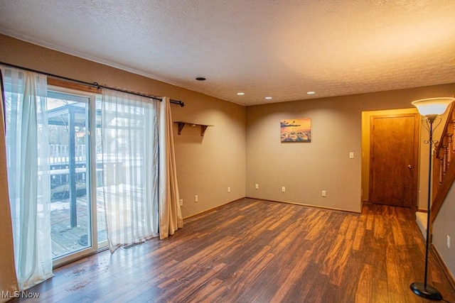 empty room with dark hardwood / wood-style floors and a textured ceiling