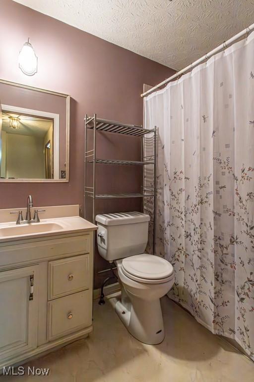 bathroom with vanity, toilet, a shower with shower curtain, and a textured ceiling