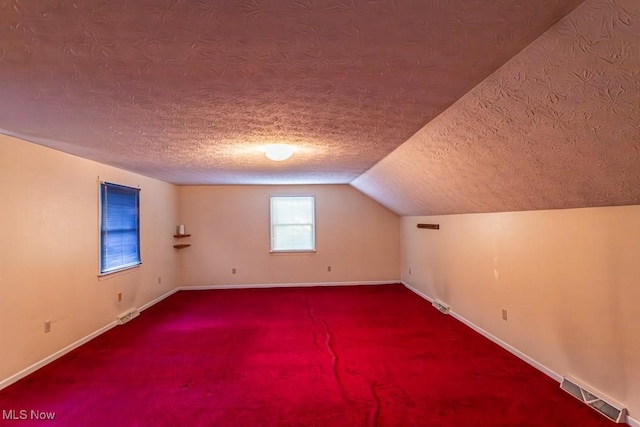 bonus room with vaulted ceiling, carpet floors, and a textured ceiling