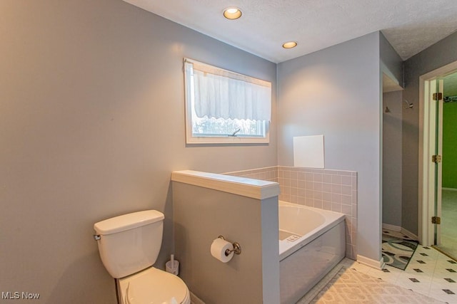 bathroom with a washtub, tile patterned flooring, and toilet