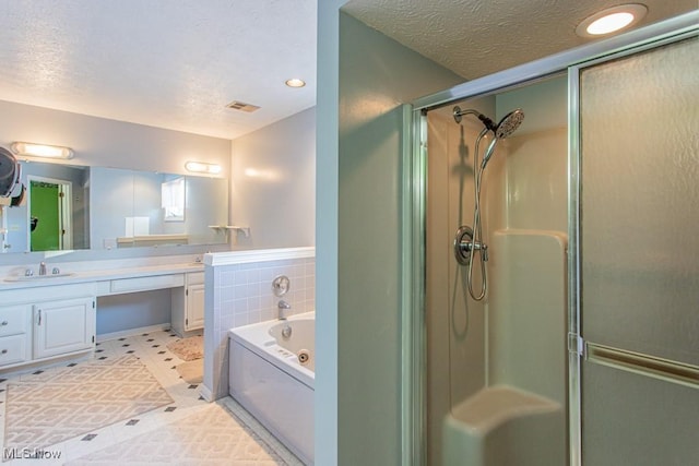 bathroom with vanity, a textured ceiling, and separate shower and tub