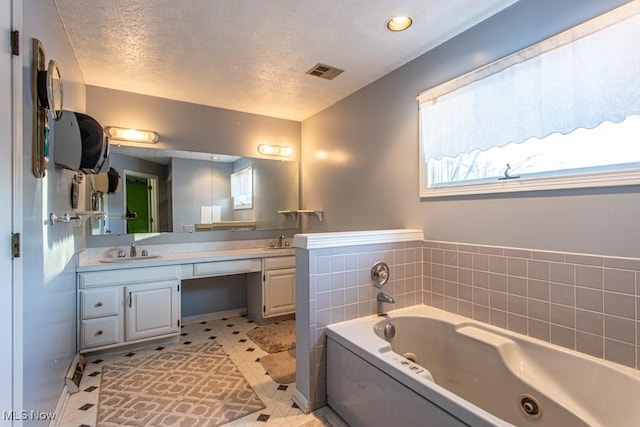 bathroom featuring vanity, a washtub, tile patterned floors, and a textured ceiling