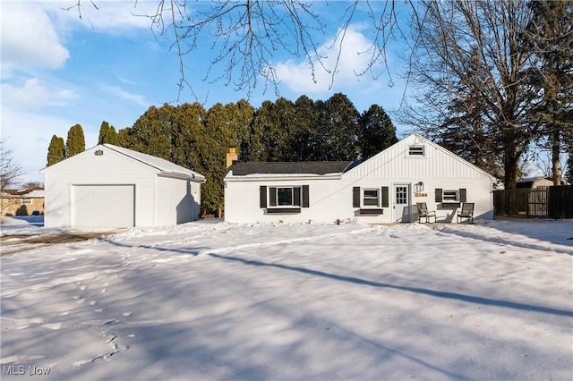 snow covered house featuring an outbuilding and a garage