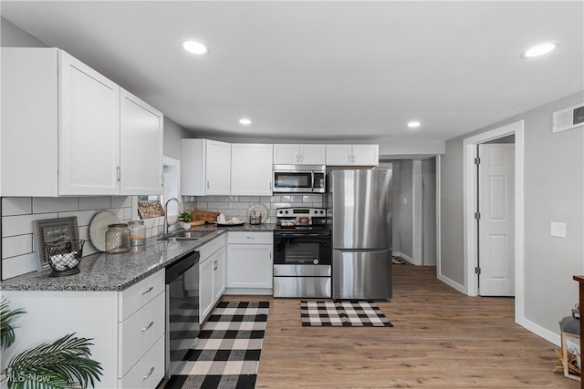 kitchen featuring sink, white cabinetry, tasteful backsplash, appliances with stainless steel finishes, and light hardwood / wood-style floors