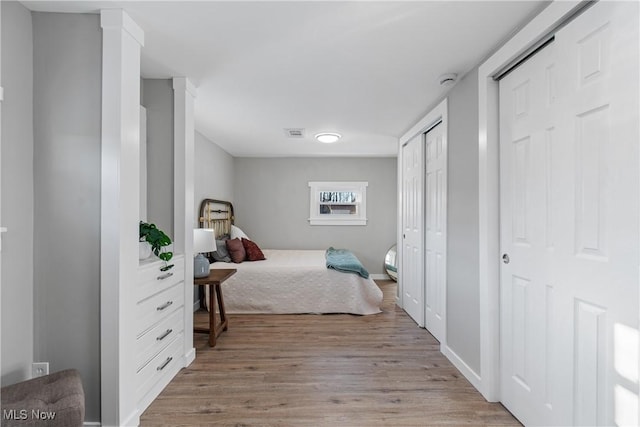 bedroom featuring two closets and light wood-type flooring