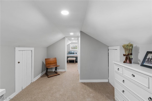 bonus room with vaulted ceiling and light carpet