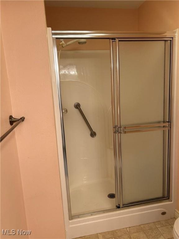 bathroom with a shower with door and toilet