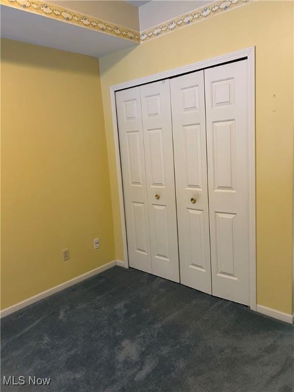 unfurnished bedroom featuring dark colored carpet and a closet