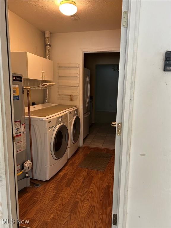 laundry room featuring a textured ceiling, washing machine and dryer, hardwood / wood-style floors, and gas water heater