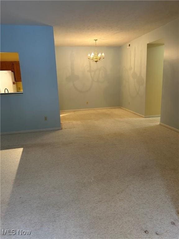 carpeted spare room with an inviting chandelier