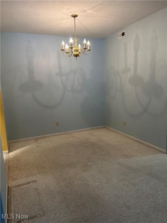 carpeted empty room with a notable chandelier