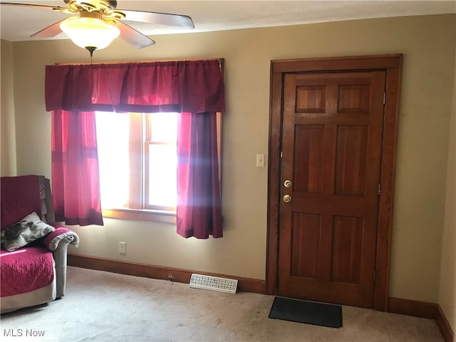 foyer with ceiling fan and carpet flooring