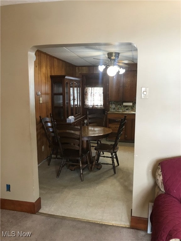 dining room with ceiling fan and wooden walls