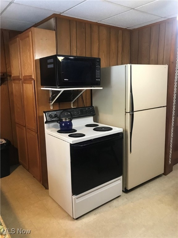 kitchen with range with electric cooktop, wooden walls, white fridge, and a drop ceiling