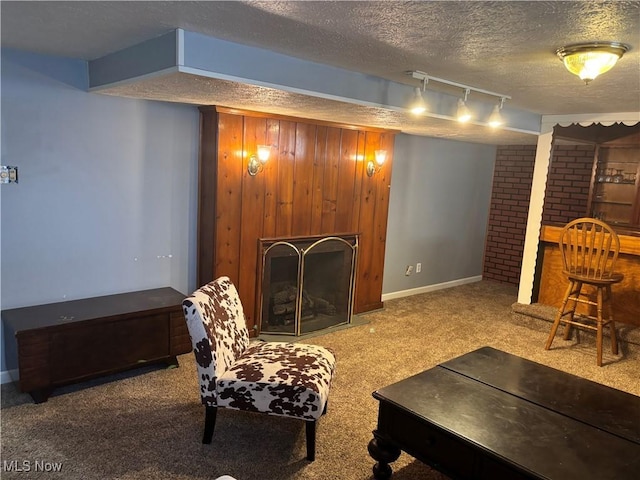 carpeted living room with wood walls, a textured ceiling, a large fireplace, indoor bar, and track lighting