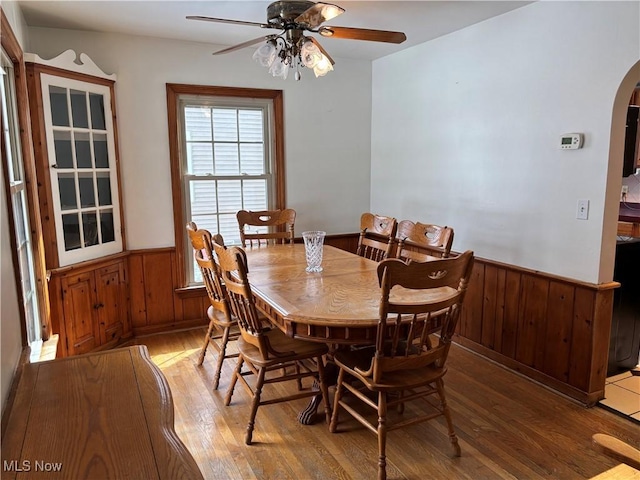 dining room with wood-type flooring, ceiling fan, and wood walls