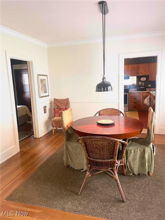 dining area with dark hardwood / wood-style flooring and ornamental molding