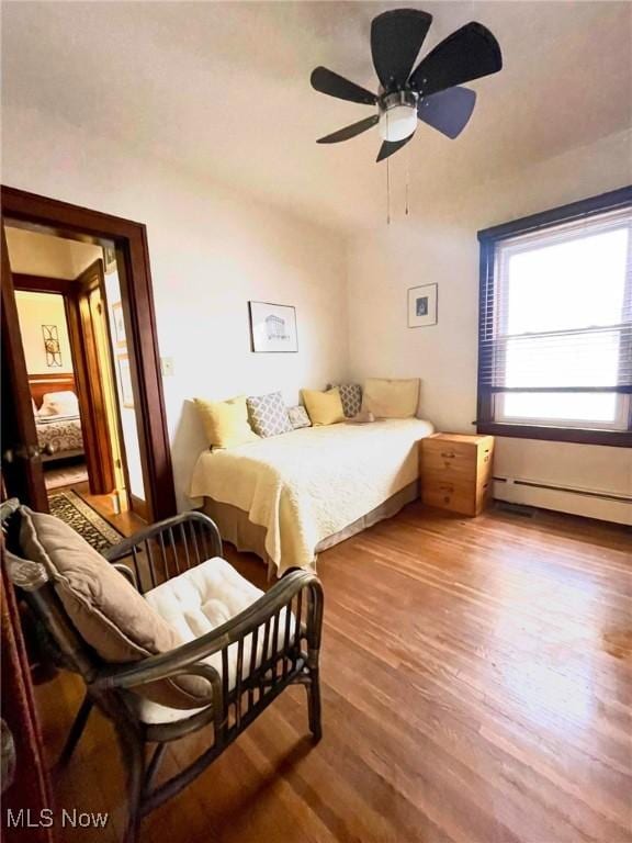 bedroom with hardwood / wood-style flooring, ceiling fan, and baseboard heating