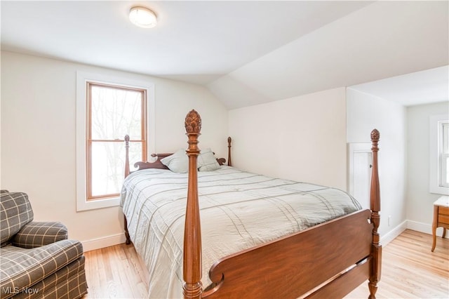 bedroom with lofted ceiling, light hardwood / wood-style floors, and multiple windows