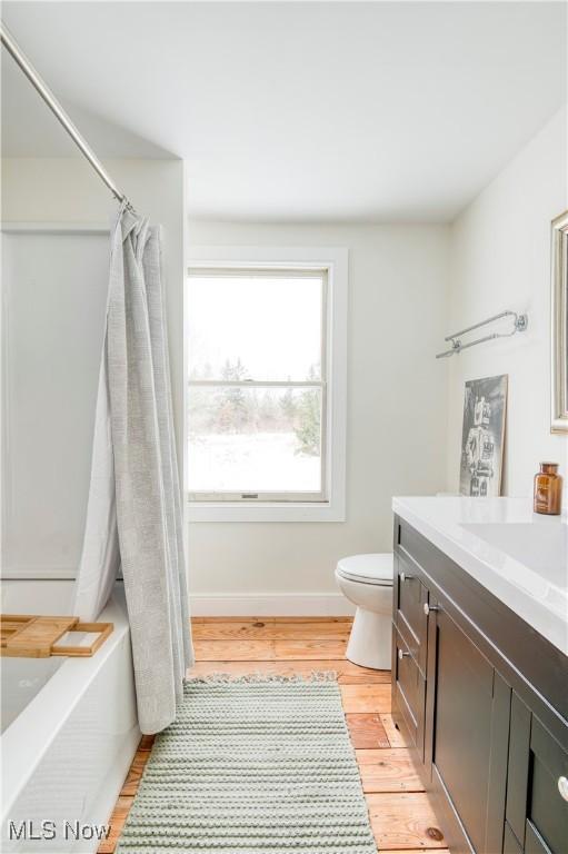 full bathroom with vanity, wood-type flooring, toilet, and shower / bathtub combination with curtain