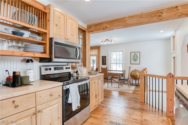 kitchen with beam ceiling, appliances with stainless steel finishes, light brown cabinetry, and light hardwood / wood-style floors