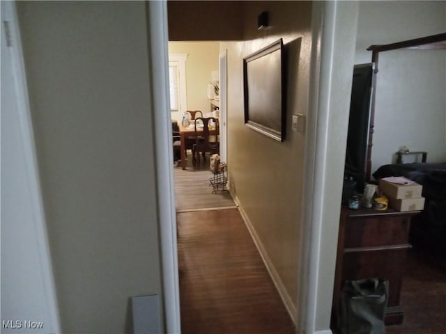 hallway featuring baseboards and dark wood-type flooring