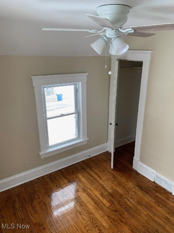 empty room featuring dark wood-style flooring, ceiling fan, and baseboards