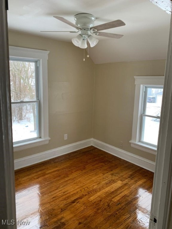 unfurnished room with lofted ceiling, wood finished floors, a ceiling fan, and baseboards