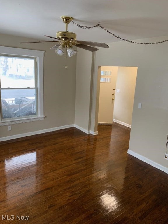 unfurnished room featuring dark wood-style flooring, ceiling fan, and baseboards