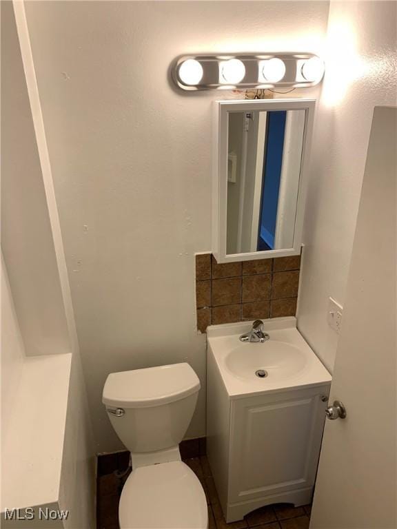 bathroom with toilet, decorative backsplash, and vanity