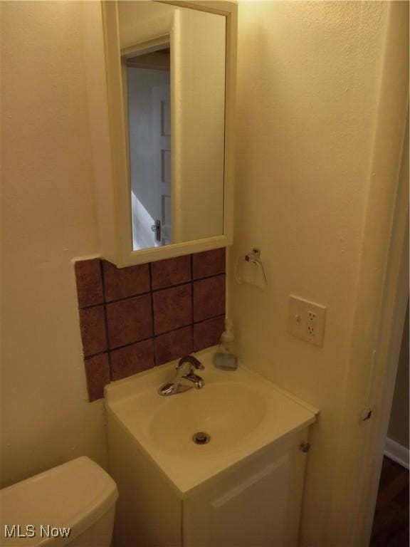 bathroom with backsplash, toilet, and vanity