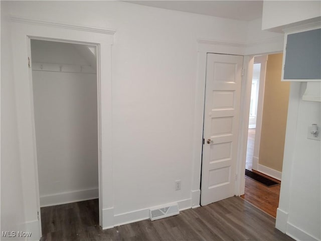 unfurnished bedroom featuring dark wood-style flooring, a closet, visible vents, and baseboards