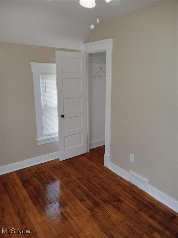 empty room featuring dark wood finished floors, visible vents, and baseboards