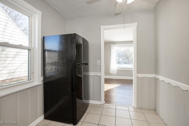 kitchen with black fridge, ceiling fan, a healthy amount of sunlight, and light tile patterned flooring