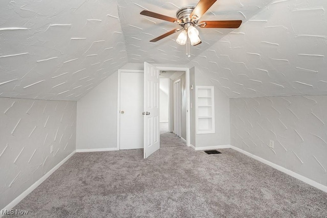 additional living space featuring vaulted ceiling, built in features, ceiling fan, and carpet flooring