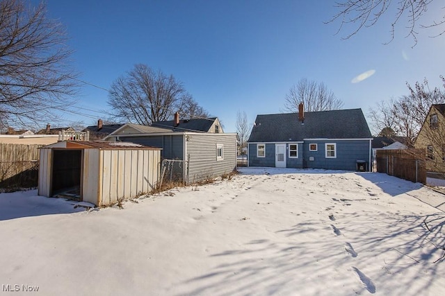 snow covered rear of property featuring a storage shed