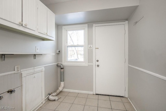 laundry area featuring light tile patterned floors and cabinets