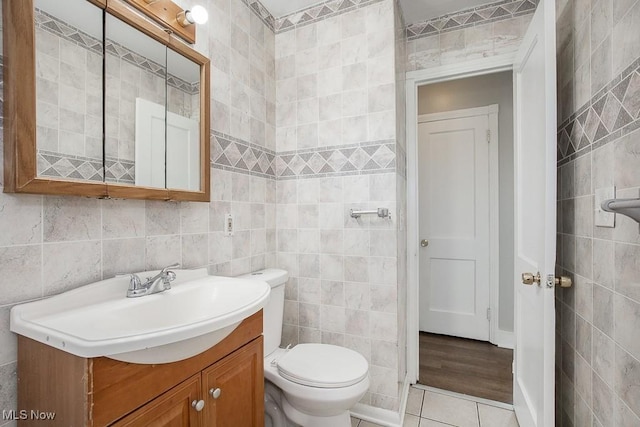 bathroom featuring tile patterned flooring, vanity, tile walls, and toilet