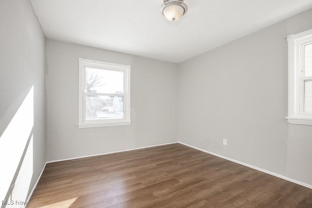 spare room with dark hardwood / wood-style flooring and a healthy amount of sunlight