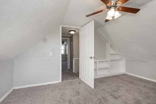 bonus room with built in shelves, vaulted ceiling, carpet floors, and a textured ceiling