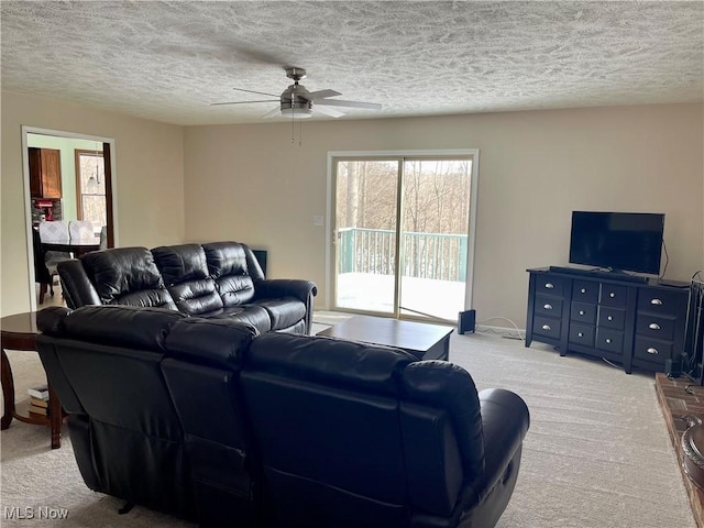 carpeted living room with ceiling fan and a textured ceiling