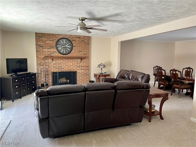 living room with ceiling fan, a fireplace, light colored carpet, and a textured ceiling