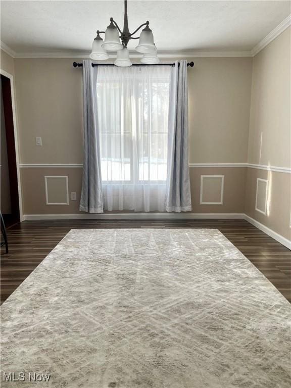 unfurnished room with a notable chandelier, crown molding, and dark wood-type flooring