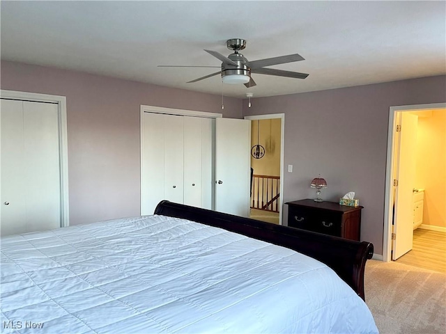 bedroom featuring light carpet, connected bathroom, two closets, and ceiling fan